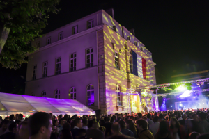 Bal des pompiers à Paris pour le 14 Juillet, caserne illuminée avec projection tricolore et foule en soirée