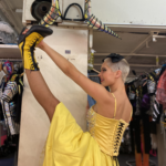 Danseuse du Paradis Latin en préparation en coulisses, jambe levée à la verticale, illustrant la souplesse issue du travail Pilates chez les artistes de cabaret